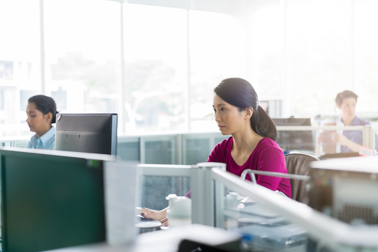 1032548806 Serious businesswoman working on computer. Female professional is sitting in cubicle. She is working at office.