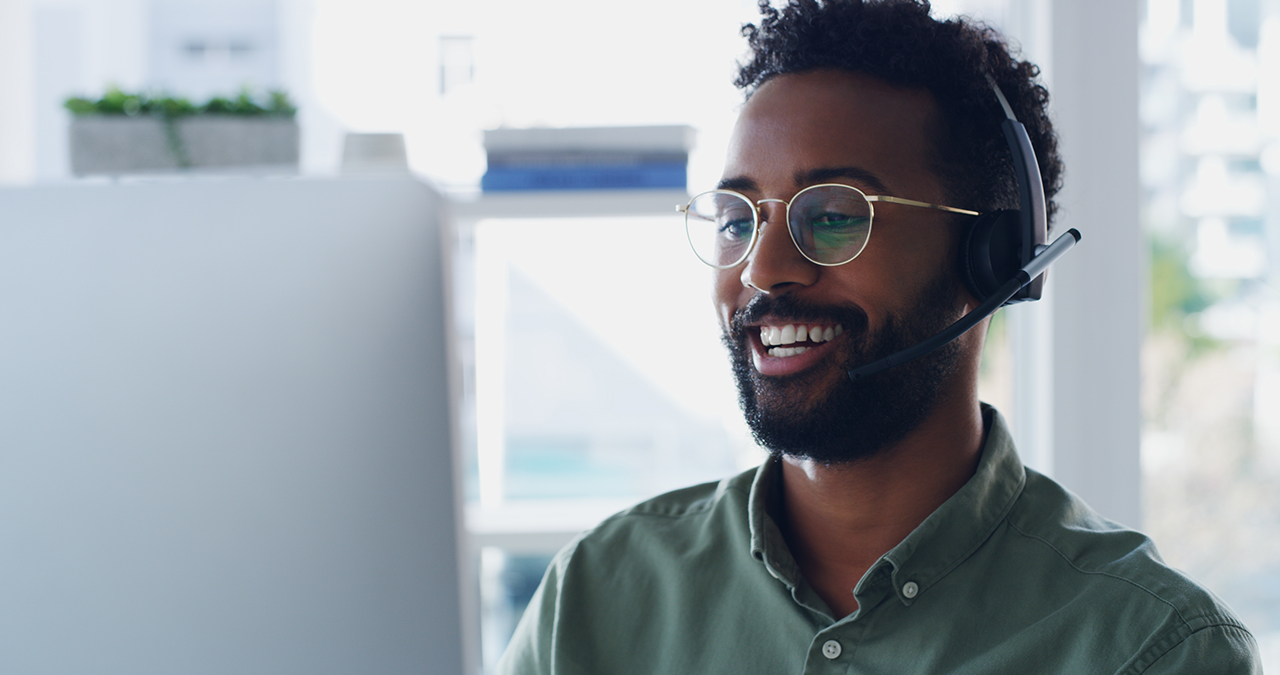 Shot of a handsome young businessman wearing headsets while working on a computer in his office