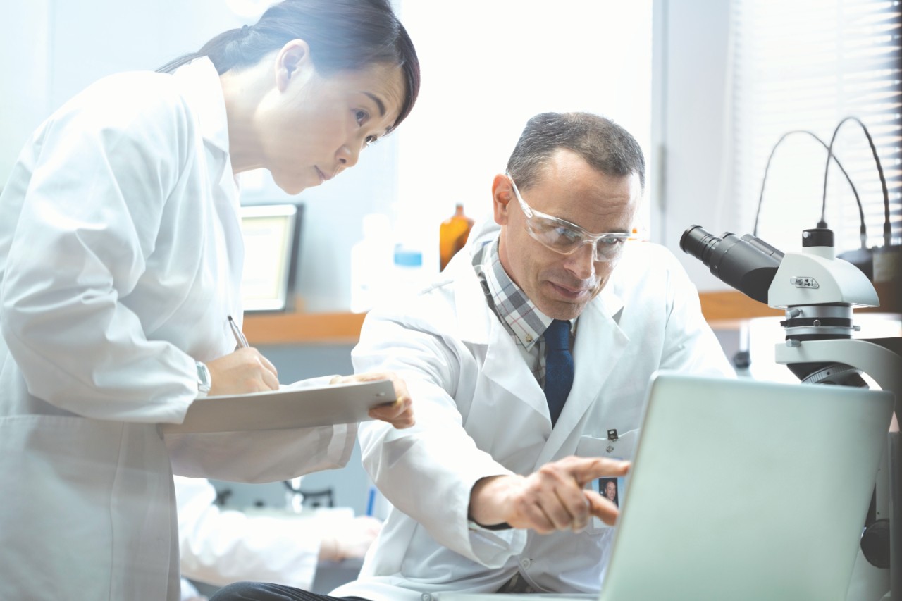 Medical scientists working at laptop in laboratory