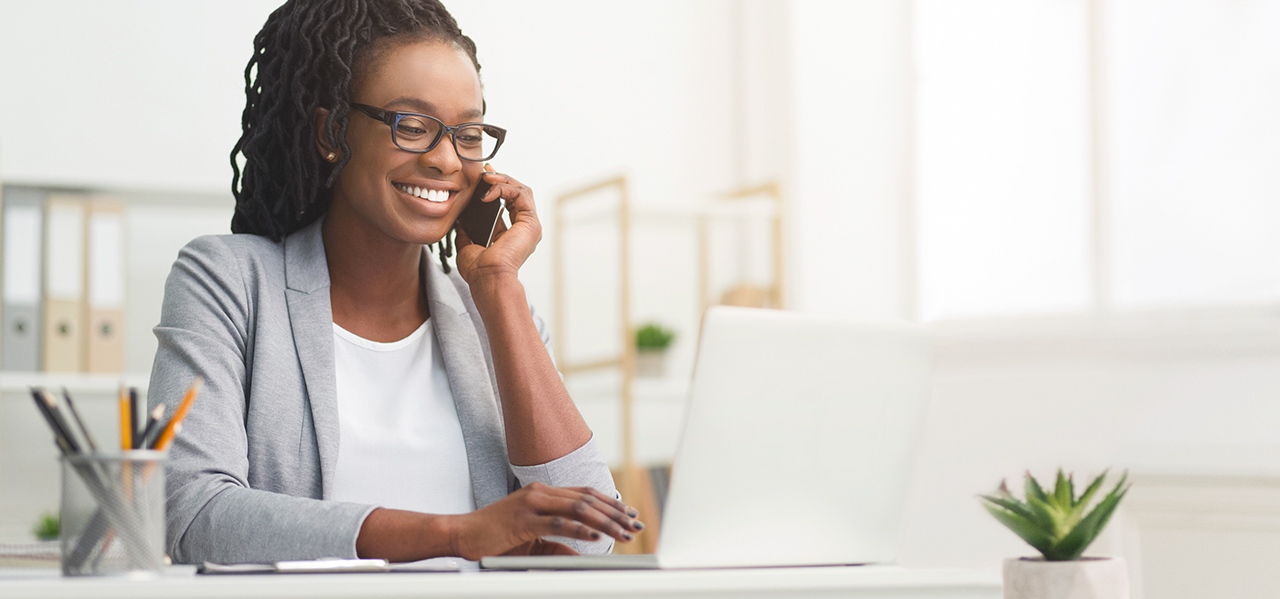 Lady Boss. Afro Businesswoman Talking On Cellphone While Working On Laptop In Modern Office, Wide Horizontal Banner, Panorama With Free Space