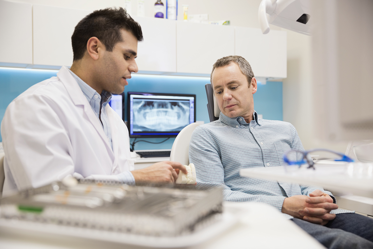 Dentist showing patient tooth model in office